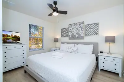 a white bedroom with a bed and two night stands at Cozy 4 BR close to Disney in Kissimmee