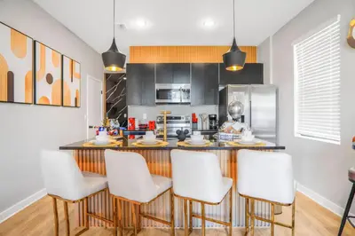 a kitchen with a bar with white stools at 3 Bedroom 8 Miles from Disney Word in Kissimmee