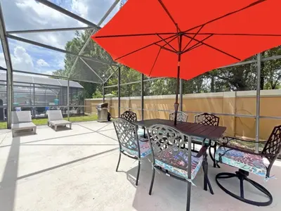 a table with a red umbrella on a patio at Endless Summer home in Kissimmee