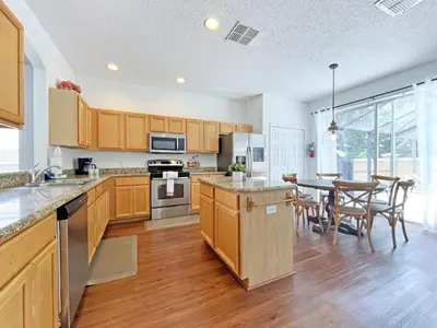 a kitchen with wooden cabinets and a table with chairs at Endless Summer home in Kissimmee