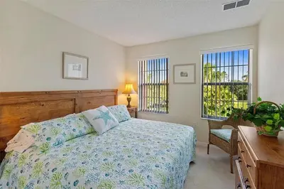 a bedroom with a bed and a desk and two windows at Ormond Retreat townhouse in Kissimmee