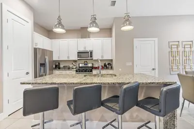 a kitchen with a large counter with chairs around it at Sunrise Shores townhouse in Orlando