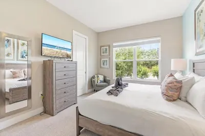 a bedroom with a bed and a dresser with a tv at Sunrise Shores townhouse in Orlando