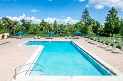 a swimming pool with chairs and umbrellas at Stylish 3BR Condo Near Disney Pool, Gym & More! in Kissimmee