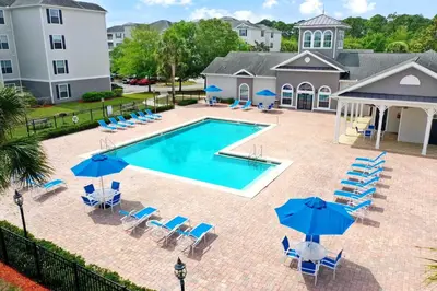 an overhead view of a swimming pool with chairs and umbrellas at Stylish 3BR Condo Near Disney Pool, Gym & More! in Kissimmee