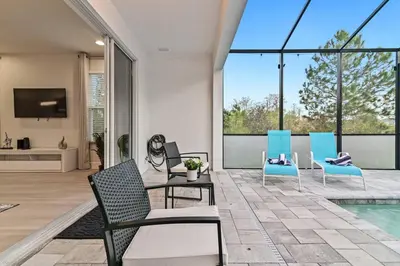 a living room with chairs and a pool at Unplug in your private oasis-NEW corner Home Pool in Orlando