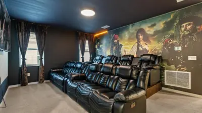 a theater room with a leather couch and a movie poster at Upstay Bella Vida Retreat w Pool Cinema and Games in Kissimmee