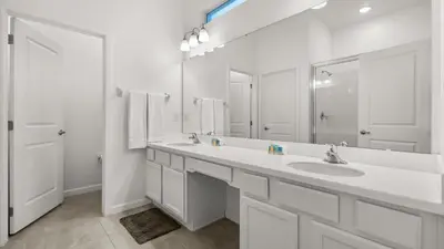 a white bathroom with two sinks and a large mirror at Upstay Bella Vida Retreat w Pool Cinema and Games in Kissimmee