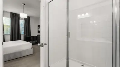 a glass shower door in a bedroom with a bed at Upstay Bella Vida Retreat w Pool Cinema and Games in Kissimmee