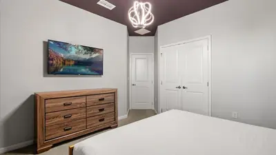 a bedroom with a bed and a dresser and a chandelier at Upstay Bella Vida Retreat w Pool Cinema and Games in Kissimmee