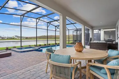 a patio with a table and chairs and a pool at Casa 7Q Storey Lake c/ Piscina, Spa e Game Room in Kissimmee