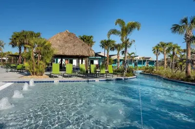 a pool at a resort with chairs and palm trees at Casa 5Q c/ Piscina Privativa - Storey Lake Resort in Kissimmee