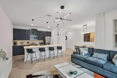 a living room with a couch and a kitchen at Casa 4Q com Piscina e Quartos Temáticos in Kissimmee