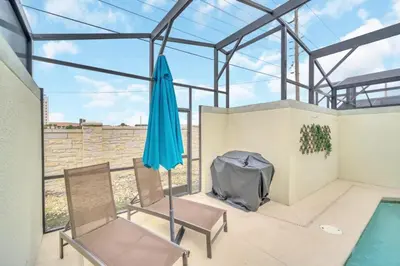 a patio with two chairs and an umbrella at Beautiful Paradise Palms Retreat townhouse in Kissimmee