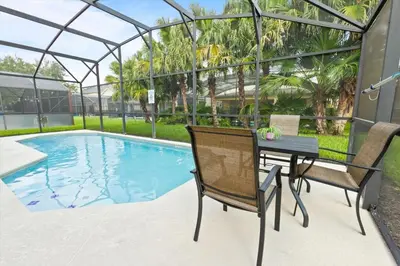 a patio with a table and chairs next to a swimming pool at Casa 5Q c/ Piscina Priv. e Sala de Jogos in Kissimmee