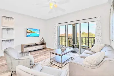 a living room with white furniture and a balcony at Upstay Pet-Friendly Condo with Pool in Orlando