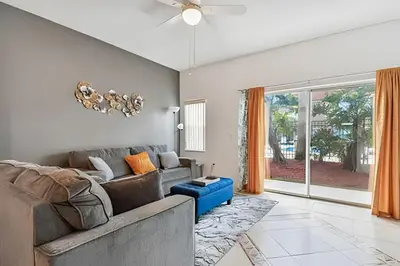 a living room with a couch and a blue stool at Casa Aconchegante no Lake Berkley – Perto da Disney in Kissimmee