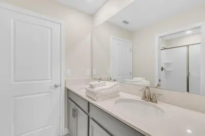 a white bathroom with a sink and a mirror at 6 Bedrooms 6 Bathrooms Storey Lake home in Orlando