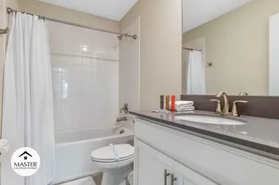 a white bathroom with a sink and a toilet at 9 Bedrooms 5 Bathrooms Storey Lake home in Kissimmee