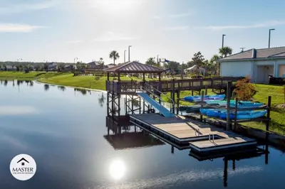 a dock with boats on the water next to a house at 9 Bedrooms 5 Bathrooms Storey Lake home in Kissimmee