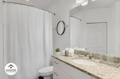 a bathroom with a sink and a toilet and a mirror at 4 Bedroom 3 Bathroom Lucaya Village townhouse in Kissimmee