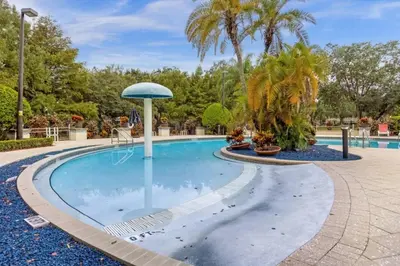 a pool at a resort with palm trees at 4 Bedroom 3 Bathroom Lucaya Village townhouse in Kissimmee