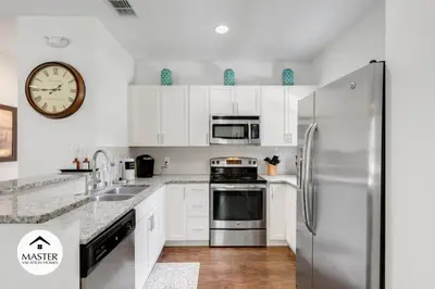 a kitchen with a refrigerator and a clock on the wall at 4 Bedroom 3 Bathroom Lucaya Village townhouse in Kissimmee
