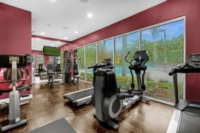 a gym with several tread machines and a large window at 3 Bedrooms 2 Bathrooms Lucaya Village townhouse in Kissimmee