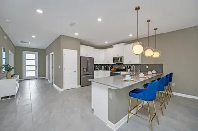 a kitchen with a large island with blue bar stools at 9 bedrooms 5 Bathrooms Storey Lake Game Room Too home in Kissimmee