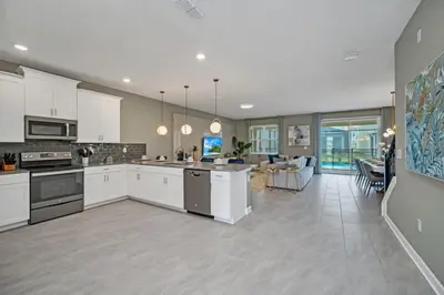a large kitchen with white cabinets and a living room at 9 bedrooms 5 Bathrooms Storey Lake Game Room Too home in Kissimmee