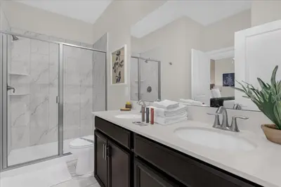 a white bathroom with a sink and a shower at 8 Bedroom & Theme Rooms For Kids In Storey Lake home in Kissimmee