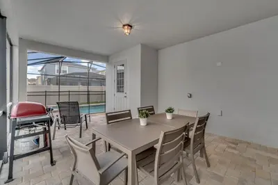 a dining room with a table and chairs and a grill at 5 Bedrooms 5,5 Bathrooms Solara home in Orlando