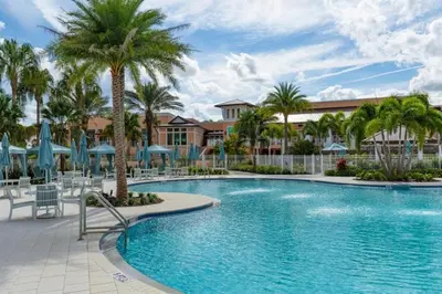 a pool at a resort with palm trees and umbrellas at 5 Bedrooms 5,5 Bathrooms Solara home in Orlando