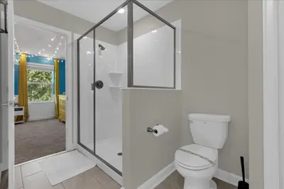 a white bathroom with a shower and a toilet at 9 Bed Storey Lake Star Wars Dream Home home in Kissimmee