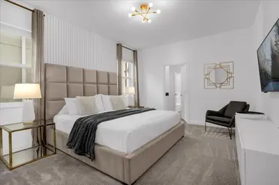 a white bedroom with a large bed and a chair at 9 bed Home Storey Lake home in Kissimmee