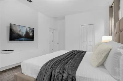 a white bedroom with a bed and a tv on the wall at 9 bed Home Storey Lake home in Kissimmee