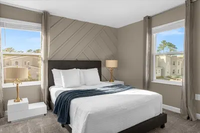 a bedroom with a large bed and two windows at 9 bed Home Storey Lake home in Kissimmee
