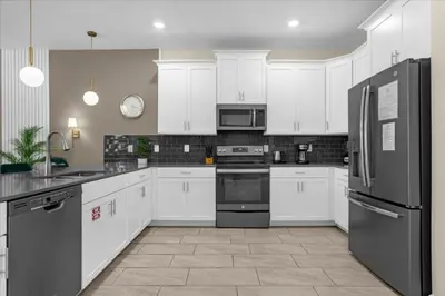 a kitchen with white cabinets and black appliances at 9 bed Home Storey Lake home in Kissimmee