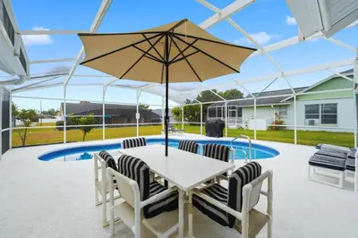 a table and chairs with an umbrella in front of a pool at Ultimate Resort Gateway in Orlando