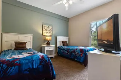 a bedroom with two beds and a flat screen tv at 4 Bedrooms 3 Bathrooms Lucaya Village townhouse in Kissimmee