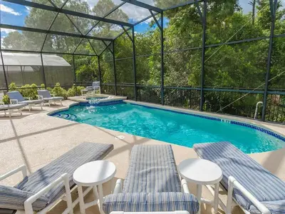 a swimming pool with two chairs and a table at Southern Comfort Private Pool Spa Near Disney! villa in Kissimmee