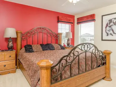 a bedroom with a large bed with a red wall at Southern Comfort Private Pool Spa Near Disney! villa in Kissimmee
