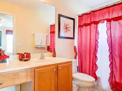 a bathroom with a red shower curtain and a toilet at Southern Comfort Private Pool Spa Near Disney! villa in Kissimmee