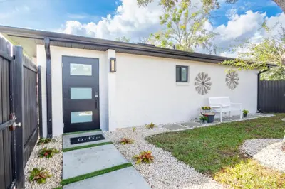 a white house with a black door and a yard at Longwood Private Suite - Near Orlando - Modern, Private Entrance, Fast WiFi in Orlando