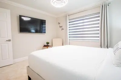 a bedroom with a white bed and a flat screen tv at Longwood Private Suite - Near Orlando - Modern, Private Entrance, Fast WiFi in Orlando