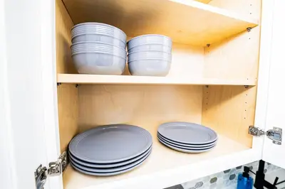 a cupboard with plates and bowls in it at Close to the Action, Peaceful When You Return in Orlando