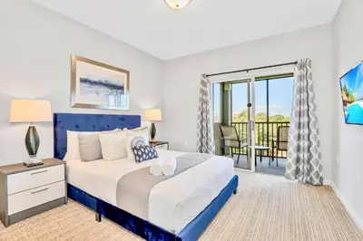 a bedroom with a king sized bed and a balcony at Modern 3BR Resort Condo with Pool near Disney in Orlando