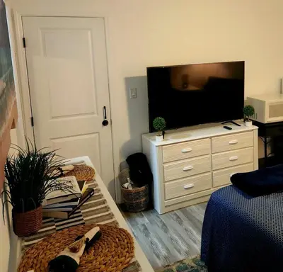 a living room with a television and a dresser at Private 1 Bedroom Suite Near Orlando Attractions in Orlando