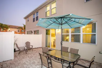 a patio with a glass table with a blue umbrella at Family Friendly 4 Bedrooms with GameRoom close to Disney in Compass Bay 5103 in Kissimmee