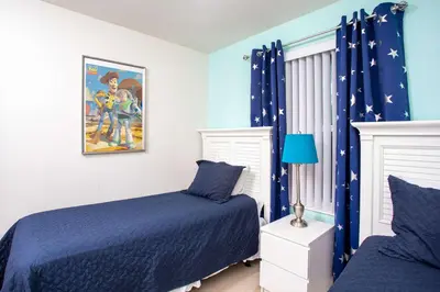 a bedroom with two beds and blue curtains at Family Friendly 4 Bedrooms with GameRoom close to Disney in Compass Bay 5103 in Kissimmee
